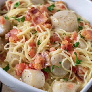 a close up front view of Cheesy Garlic Bacon Scallops and Linguine served in a white dish