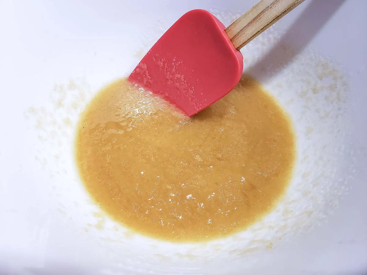 butter, oil, and sugar in a bowl with a red spatula.