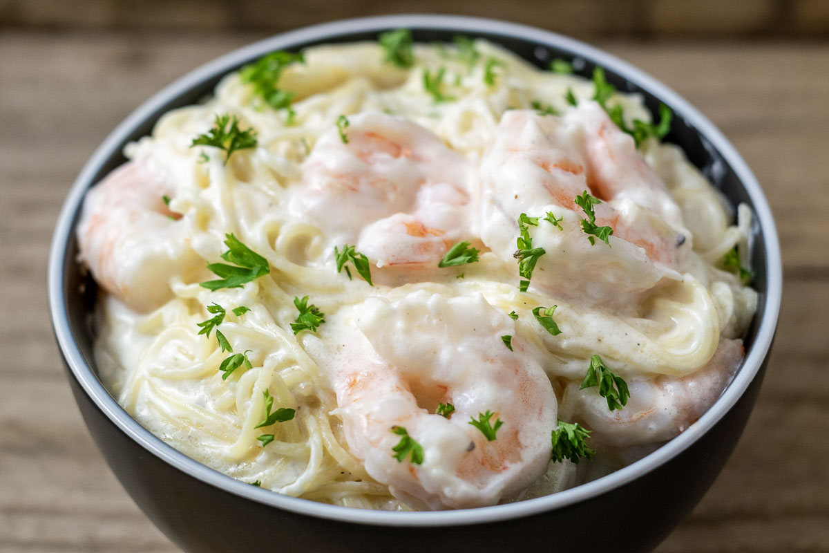 a close up front view of shrimp alfredo in a bowl