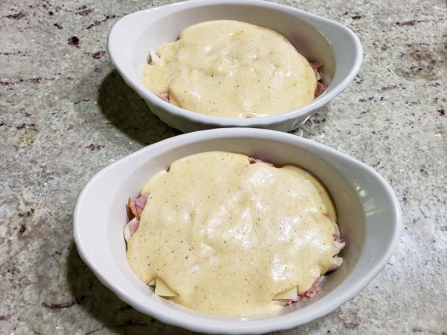 cordon bleu sauce layered over meat and cheese in baking dishes