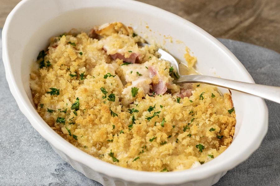a close up front view of Low-carb Chicken Cordon Bleu Casserole with a spoon digging into the casserole