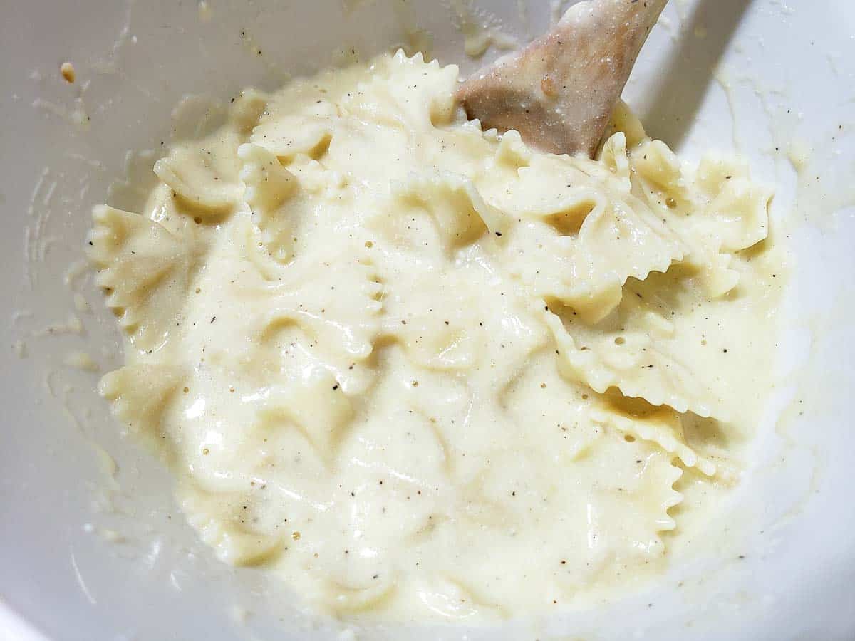 pasta and white sauce mixed in a bowl with a spoon.
