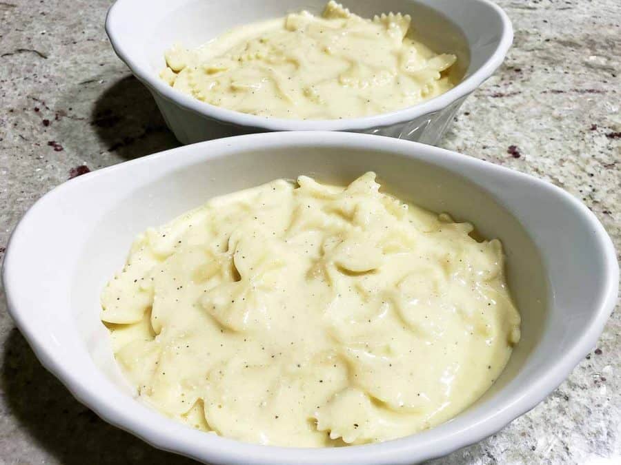 pasta and white sauce mixture layered in two baking dishes