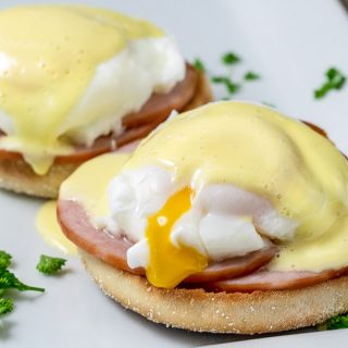 two Easy Eggs Benedict on a platter with some parsley