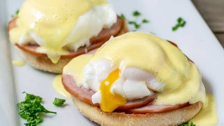 two Easy Eggs Benedict on a platter with some parsley