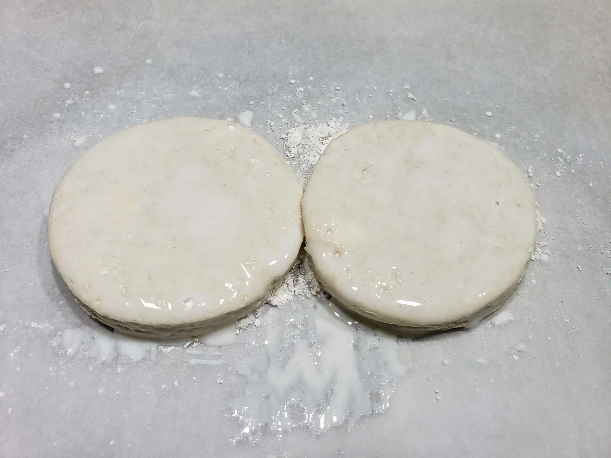 milk brushed over two homemade biscuits