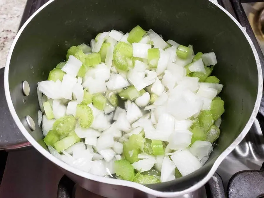 onion, celery and chicken broth cooking in a pan.