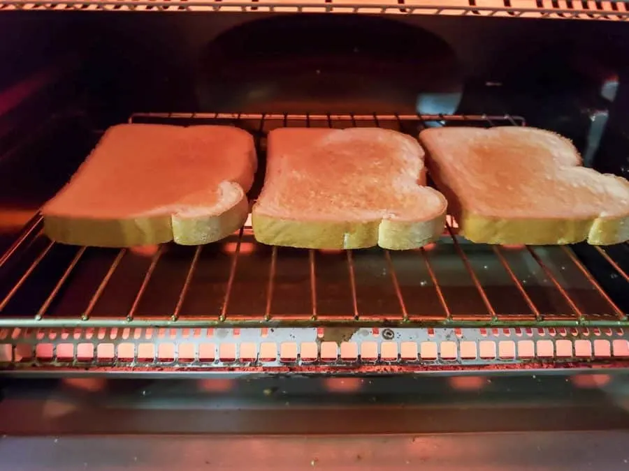 3 slices of bread toasting in a toaster oven.