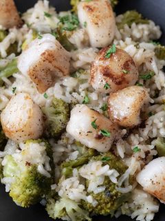 close up view of Scallops with Rice and Broccoli with parmesan cheese and brown butter drizzle on a plate