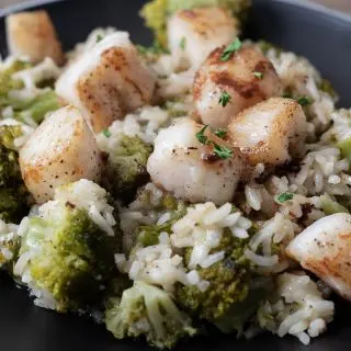 Scallops with Rice and Broccoli with parmesan cheese and brown butter drizzle on a plate