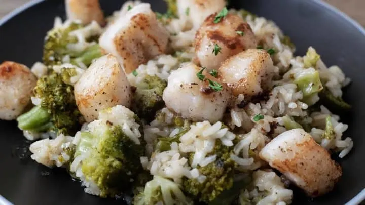 Scallops with Rice and Broccoli with parmesan cheese and brown butter drizzle on a plate