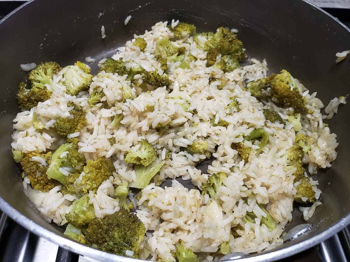 parmesan rice and broccoli cooking in a pan.
