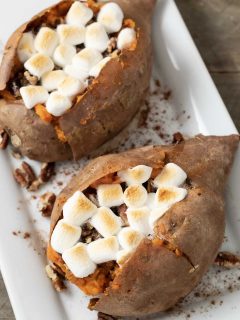 two sweet potatoes with marshmallow, brown sugar, butter, and pecan stuffing.