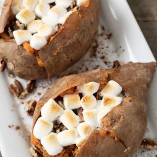 two sweet potatoes with marshmallow, brown sugar, butter, and pecan stuffing.