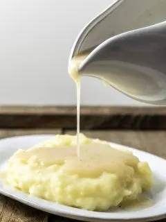 easy 5 ingredient chicken gravy being poured over mashed potatoes