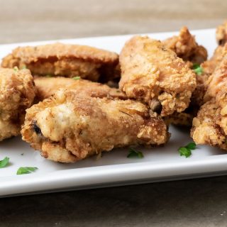 crispy deep fried chicken wings on a white platter