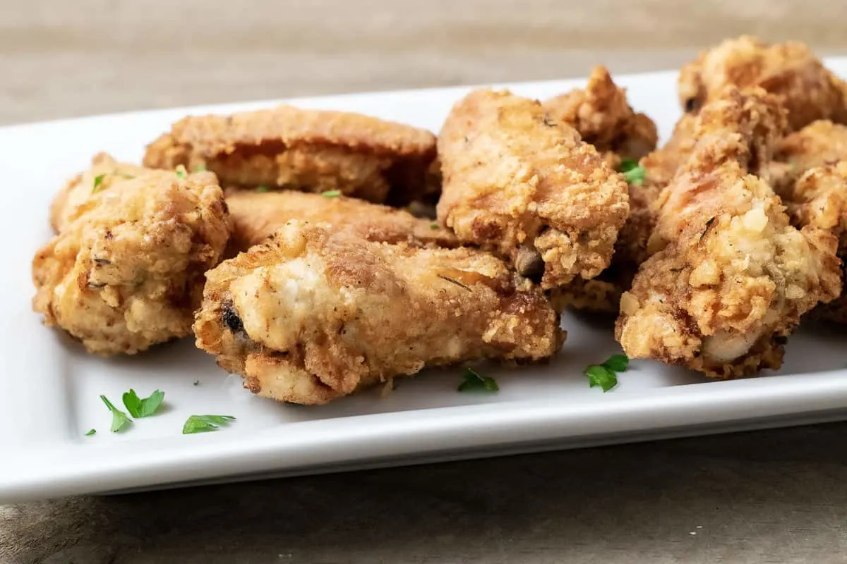 crispy deep fried chicken wings on a white platter
