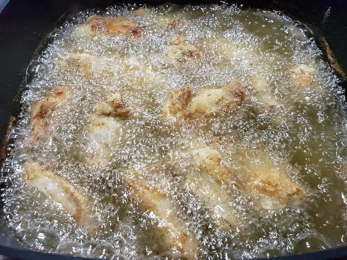 chicken wings and drummies deep frying in an electric skillet