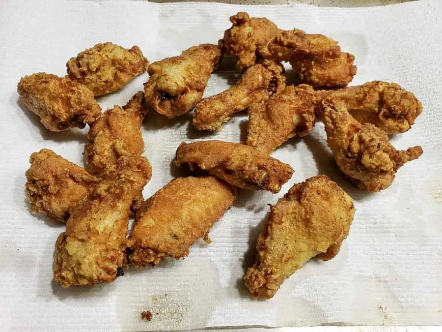 easy crispy deep fried chicken draining on a paper towel lined baking sheet.