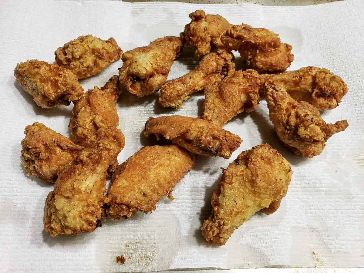 easy crispy deep fried chicken draining on a paper towel lined baking sheet