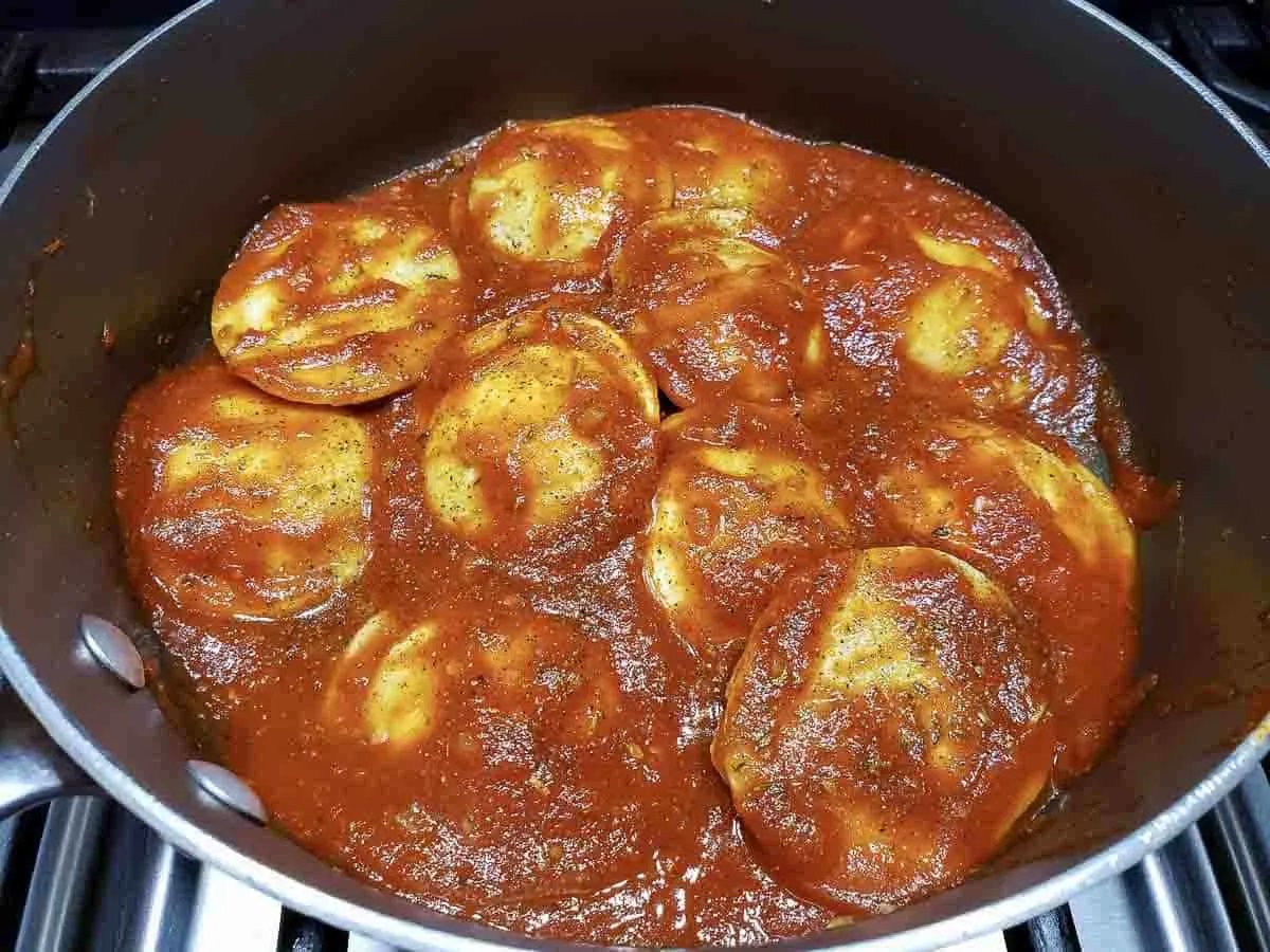 frozen ravioli, Italian seasoning, and pasta sauce in a pan