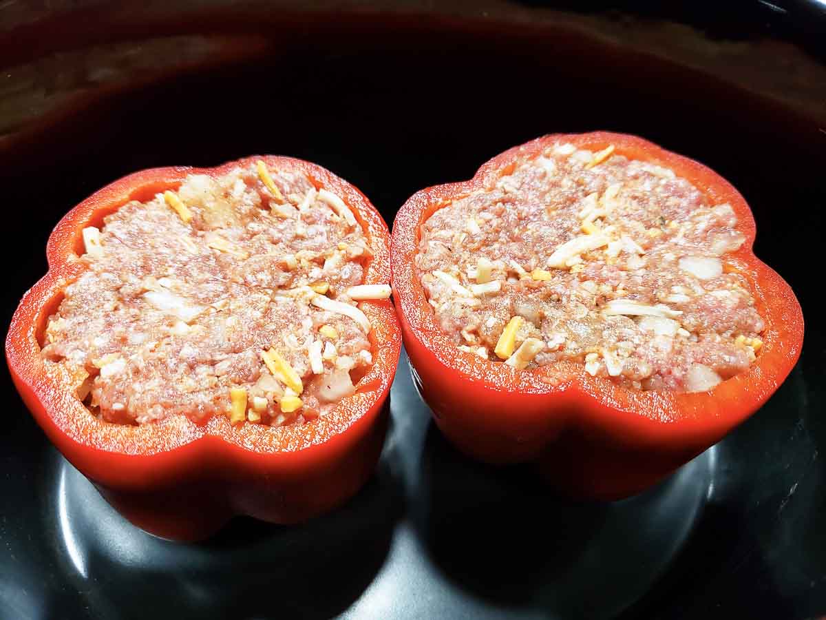 two mexican stuffed peppers in a slow cooker crock pot.
