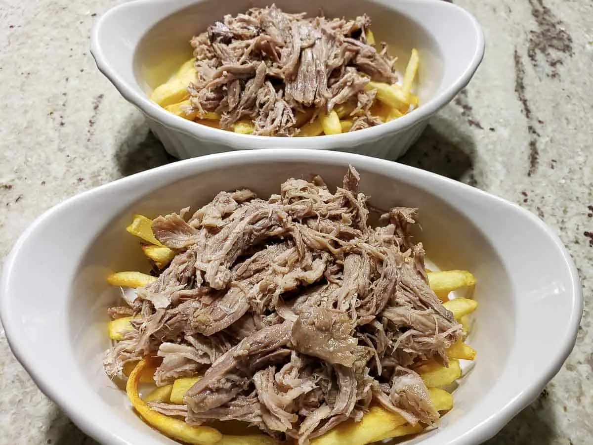 Kalua pulled pork on top of French fries in two casserole dishes