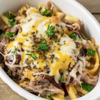 a baking dish filled with loaded bbq fries, Kalua pulled pork, and melted cheese