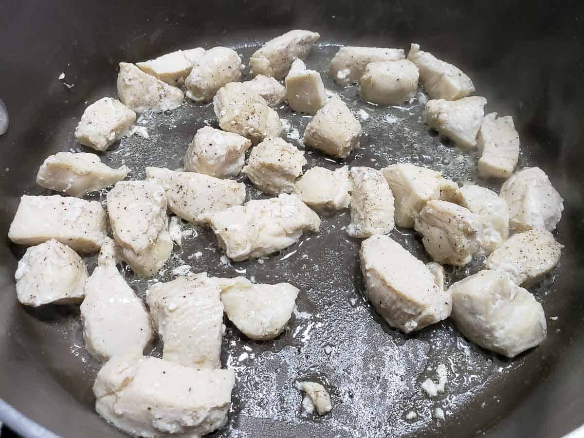 diced chicken cooking in a frying pan.