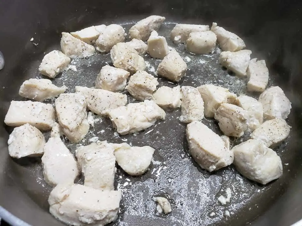 diced chicken cooking in a frying pan.