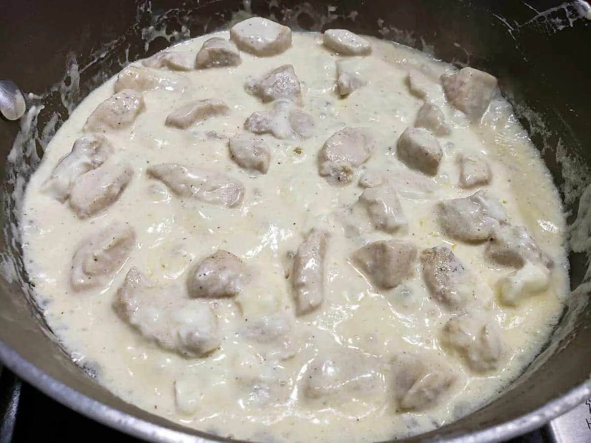 chicken cooking in cream cheese and butter sauce.