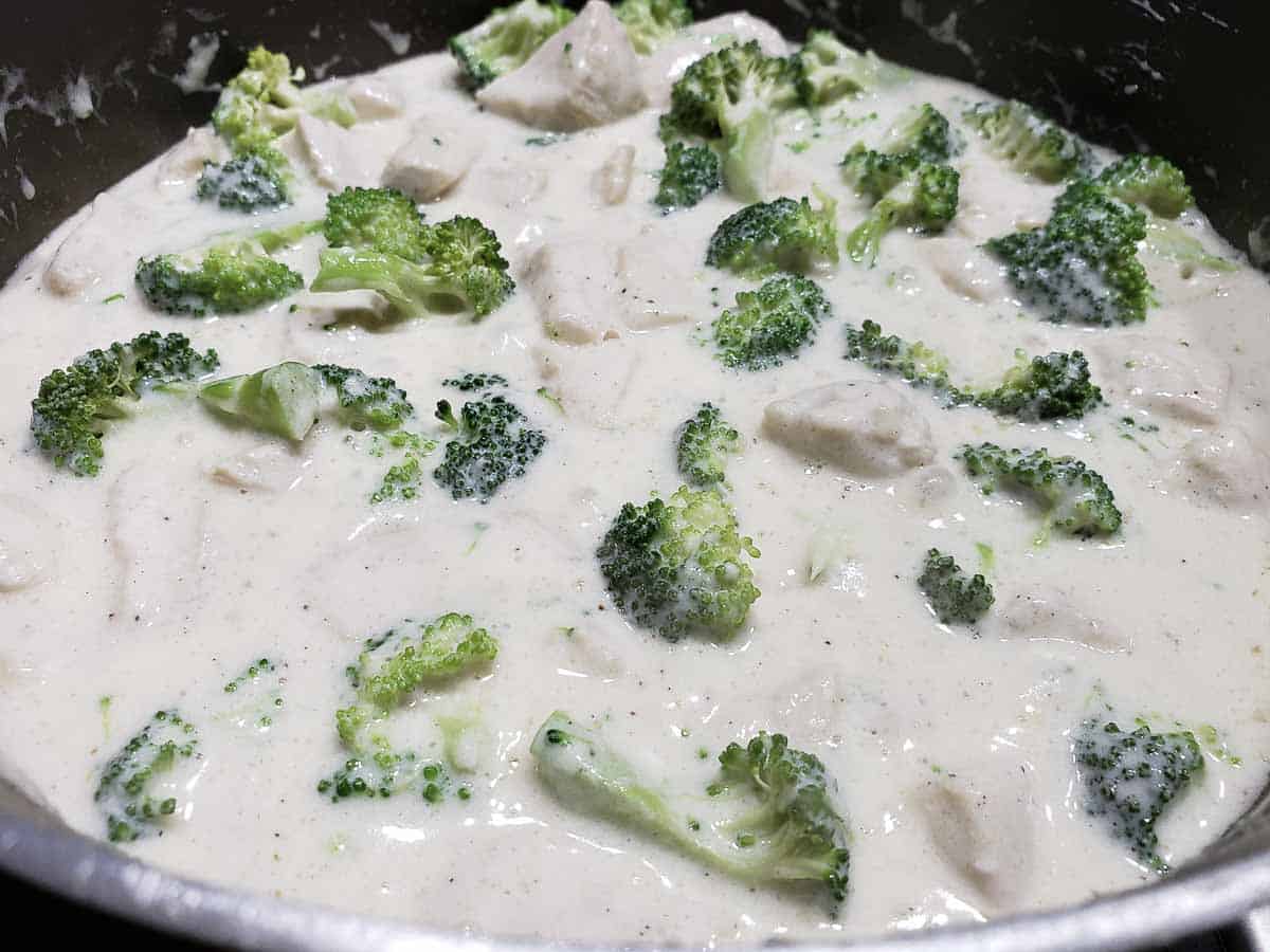 chicken and fresh broccoli cooking in alfredo sauce made from scratch.