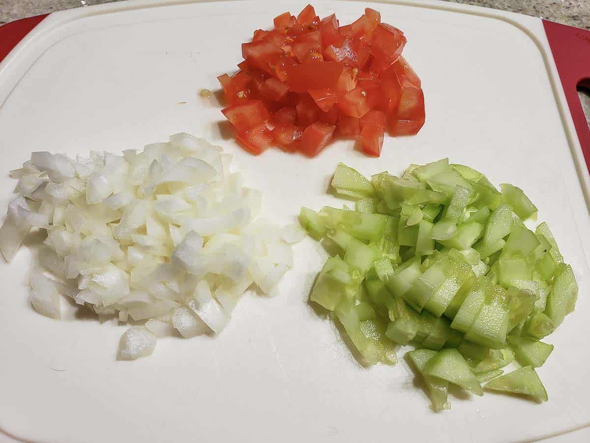onion, tomato, and cucumber diced on a cutting board