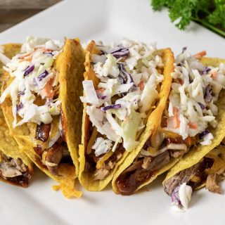 a platter filled with five Smoky BBQ Pulled Pork Tacos with Slaw