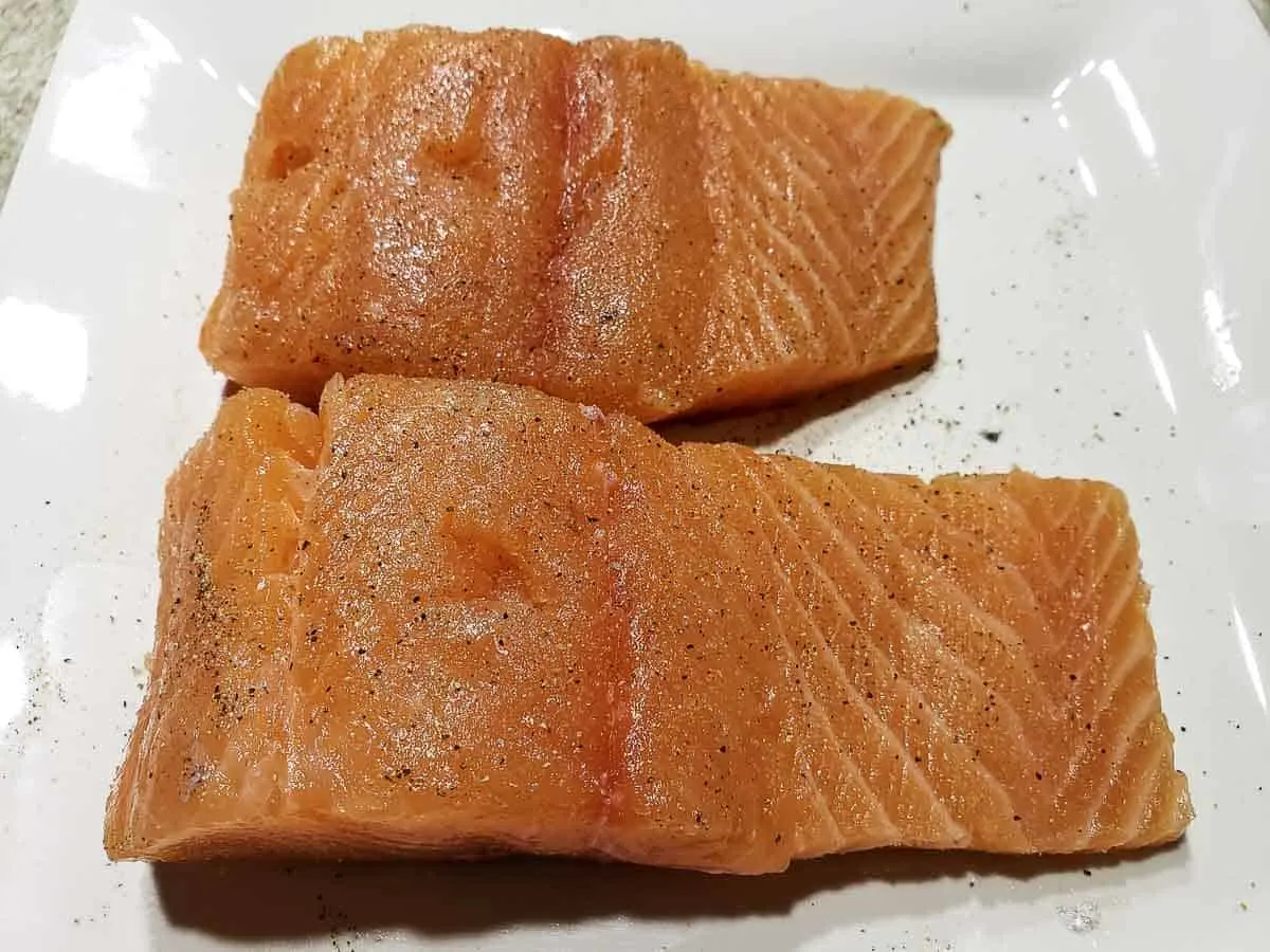 two salmon filets seasoned with salt and pepper on a plate