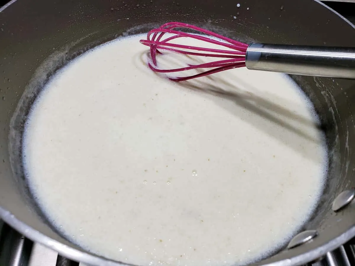 milk whisked into flour mixture in a pan.