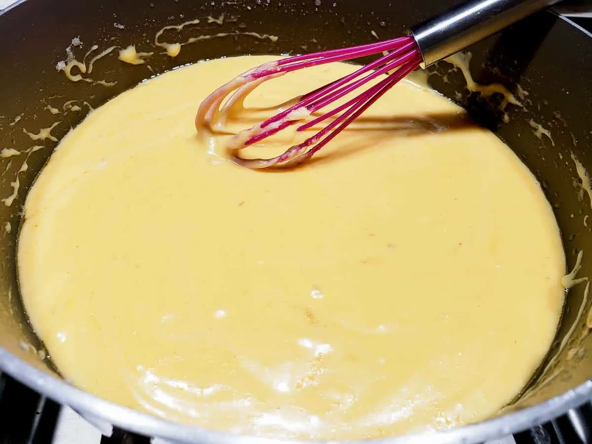 cheese melted into milk mixture in a pan.