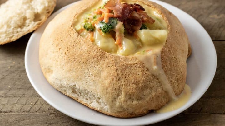 Baked Bread Bowl filled with soup on a plate.