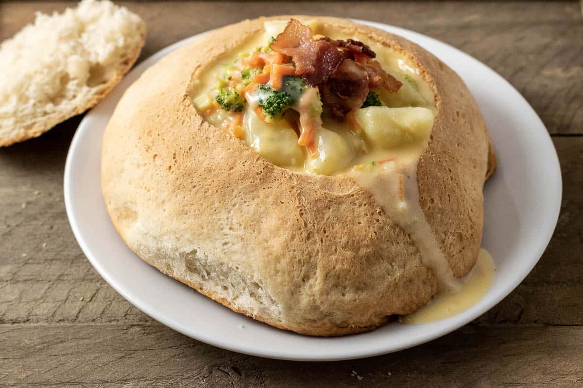 Baked Bread Bowl filled with soup on a plate.