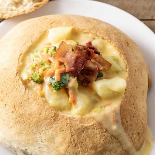 a homemade bread bowl filled with cheesy vegetable soup.