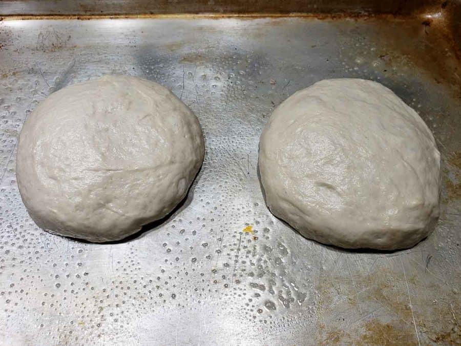 two round dough balls resting on a baking sheet