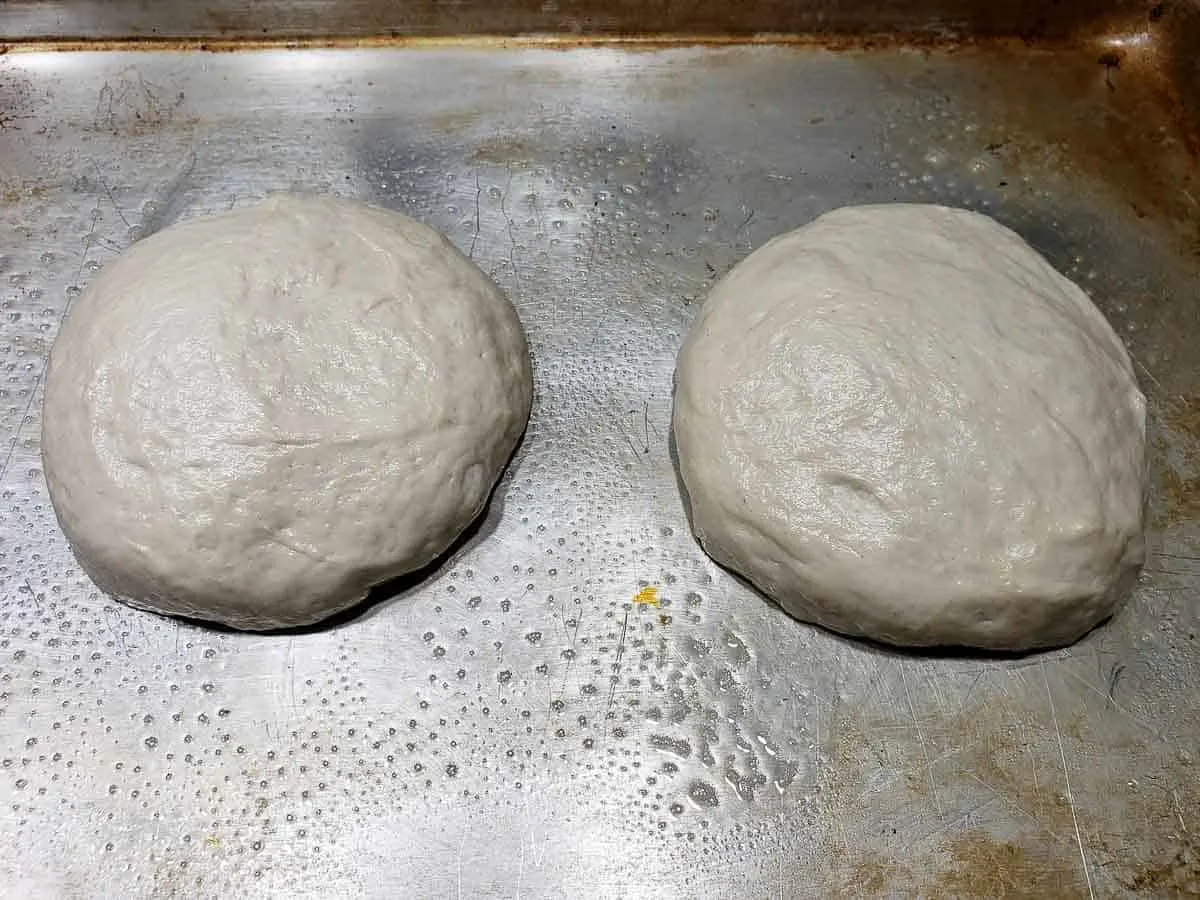 two round dough balls resting on a baking sheet.