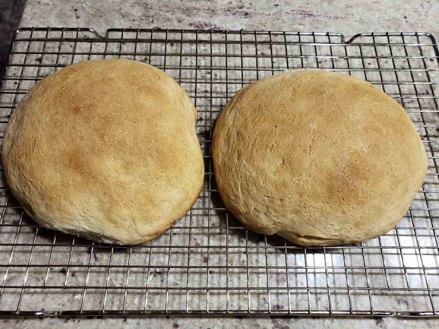 two baked bread bowls cooling on a rack
