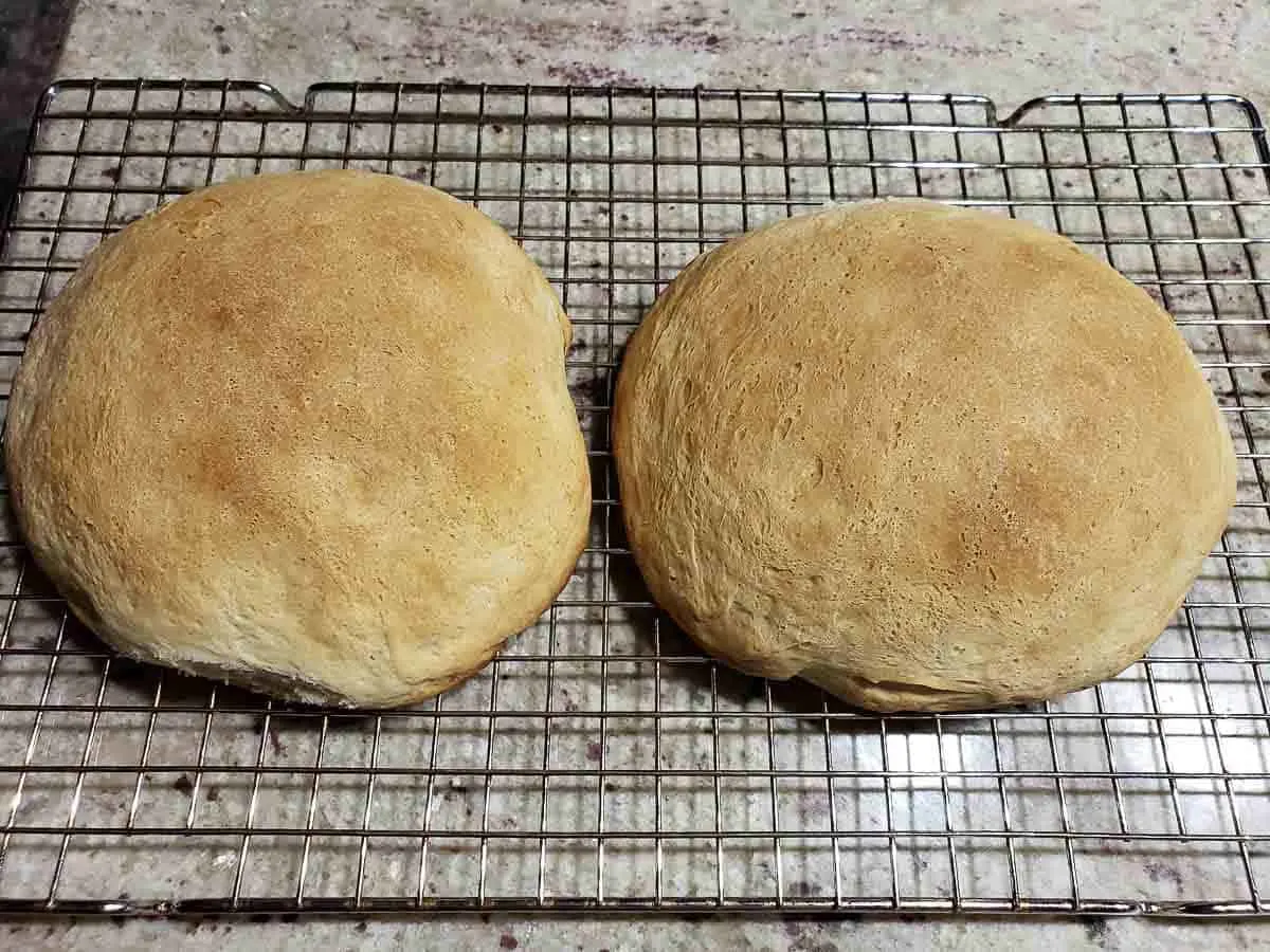 two baked bread bowls cooling on a rack.