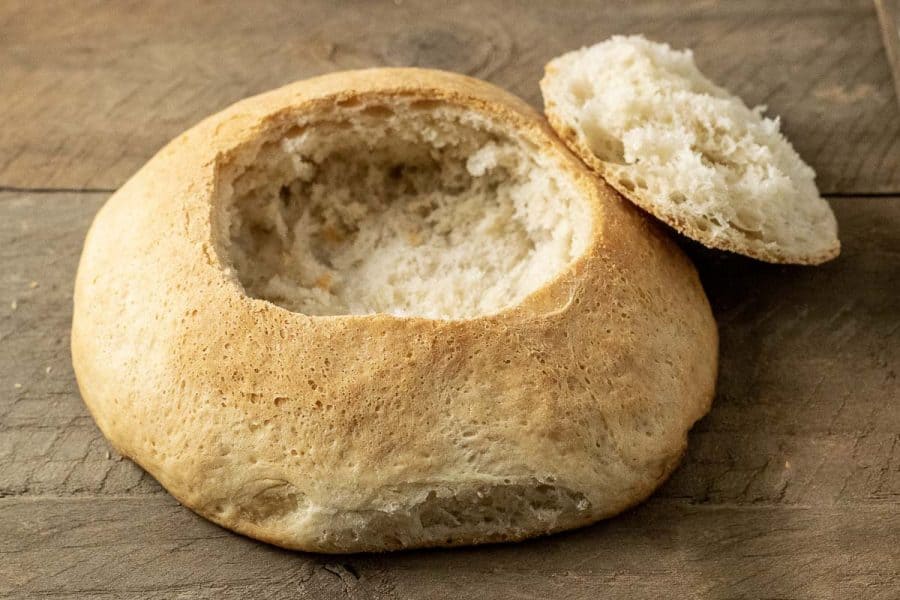an empty bread bowl with the lid resting against it.