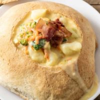 a homemade bread bowl filled with cheesy vegetable soup.