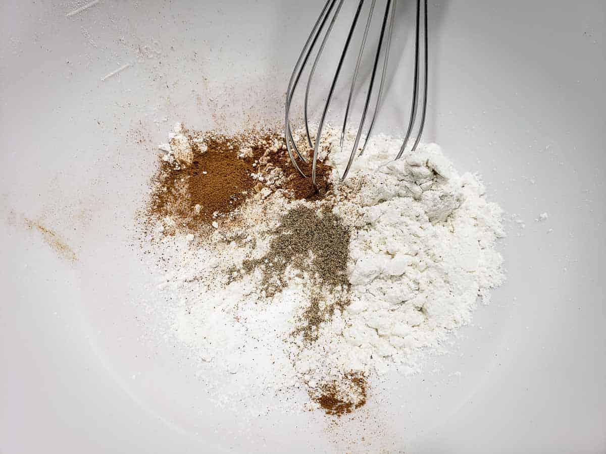 flour and spices being whisked in a mixing bowl.