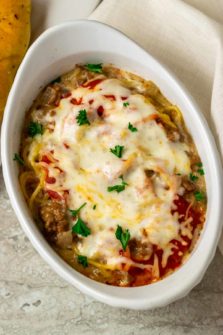 a white baking dish filled with spaghetti noodles, ground beef, red sauce, and cheese
