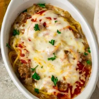 a white baking dish filled with spaghetti noodles, ground beef, red sauce, and cheese