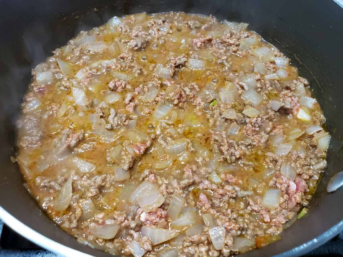 onion and ground beef cooking in a brown sauce